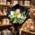 Elegant rose bouquet wrapped in black paper with baby’s breath, displayed in a gift shop setting