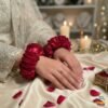 Bride wearing fresh red rose gajray on hands, traditional Pakistani wedding floral jewellery